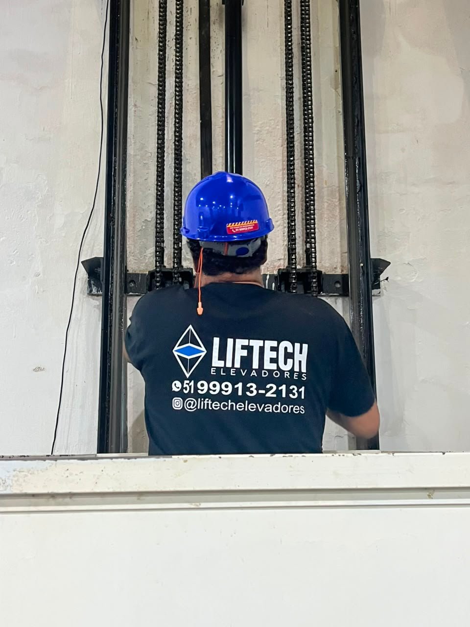 Técnico da Liftech Elevadores trabalhando no poço de um elevador, ajustando as guias